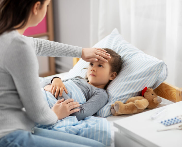 family, health and people concept - mother measuring temperature of sick daughter lying in bed at home with hand