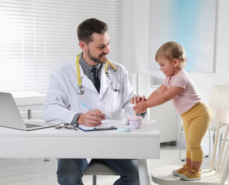 Pediatrician playing with cute baby in clinic